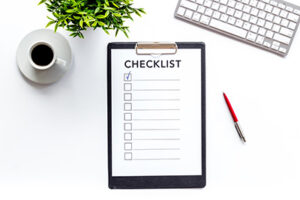 Checklist on white office background top view.